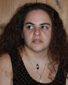 white woman with long wavy brown hair, her eyes are looking to the side, expression is not smiling a little more surprise