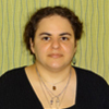 whie woman with brown hair worn up, black shirt, background is green with vertical stripes